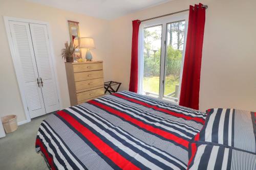 a bedroom with a striped bed and a window at Southern Dream - Water views & screened porch! in Deep Hole