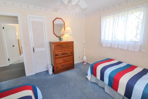 a bedroom with a bed and a dresser and a mirror at Southern Dream - Water views & screened porch! in Deep Hole