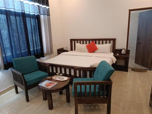 a bedroom with a bed and two chairs and a table at Brahma Heritage-Pool with Nature in Pushkar