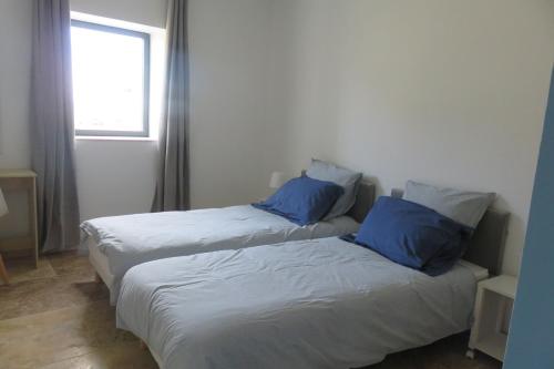 two beds with blue pillows in a room at Le Catalpa in Normier