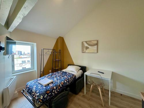 une petite chambre avec un lit et une table dans l'établissement Charmant Studio Bd Lafayette tout équipé 16, à Clermont-Ferrand