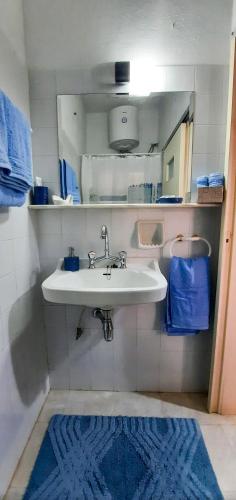 a bathroom with a white sink and a blue rug at "Vintage style" mini apartment in Áyios Spirídhon