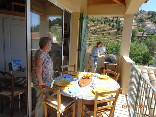 2 femmes debout sur une terrasse couverte avec une table sur un balcon dans l'établissement bastidon, 5 people near beach, sea view, quiet, au Lavandou