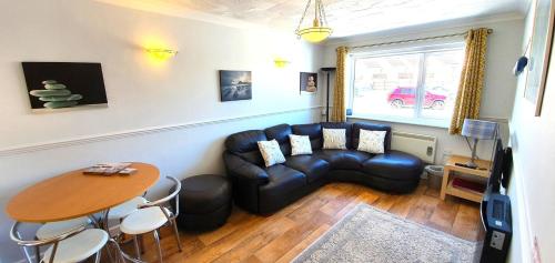 ein Wohnzimmer mit einer Ledercouch und einem Tisch in der Unterkunft 7 Penhale in Perranporth