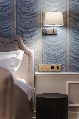a bedroom with a bed and a lamp on a wall at Hotel Unicus Palace Old Town - Destigo Hotels in Kraków