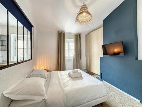 - une chambre avec un grand lit blanc et un mur bleu dans l'établissement Cosy Appartement, St Sebastien, à Lyon