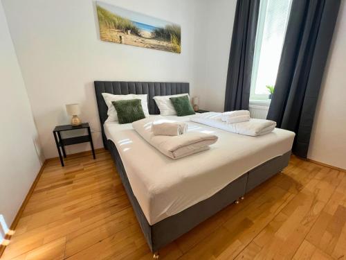 a bedroom with a bed with white sheets and green pillows at Leoben City Apartments - Premium Apartments 24 7 in Leoben