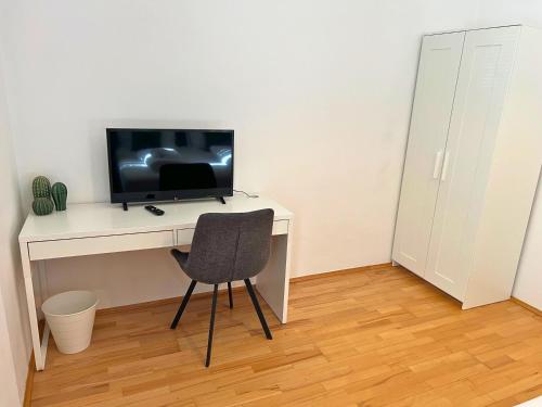 a desk with a television and a chair in a room at Leoben City Apartments - Premium Apartments 24 7 in Leoben