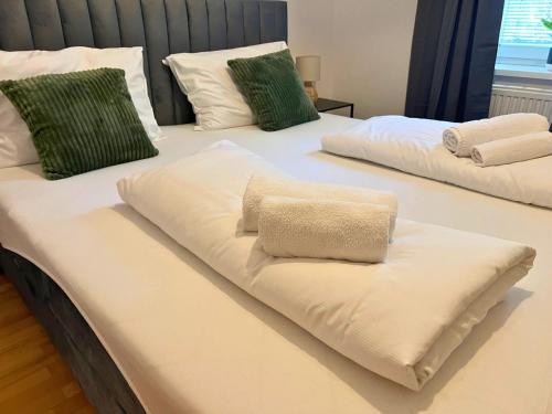 two beds with white sheets and green pillows at Leoben City Apartments - Premium Apartments 24 7 in Leoben