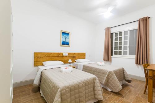 a room with two beds and a window at Sagrados Corações - Pousada in Pindamonhangaba