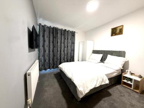 バーミンガムにあるEn-suite Rooms in beautiful Bournville Villageのベッドルーム(白いベッド1台、黒いカーテン付)