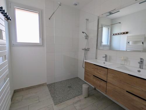 une salle de bain avec un lavabo, une douche et un miroir dans l'établissement Maison neuve de plain-pied avec extérieur, à Pornic
