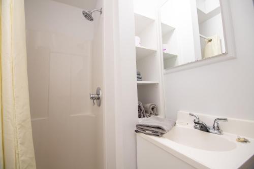 a white bathroom with a sink and a shower at Appartements-Hôtel les Mouettes in Sept-Îles