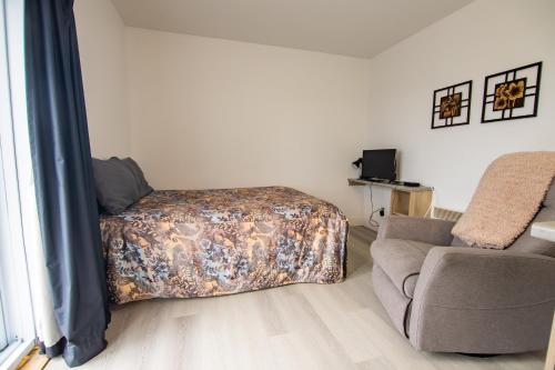 a bedroom with a bed and a couch and a chair at Appartements-Hôtel les Mouettes in Sept-Îles