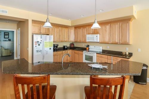 a kitchen with wooden cabinets and a granite counter top at Sunset Bay Villa 116 - Waterfront with shared pool! in Chincoteague
