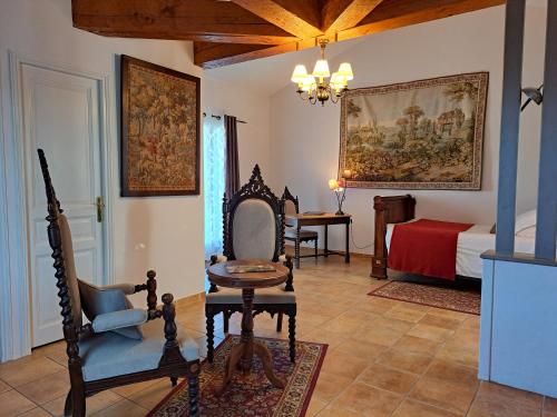 a room with a bed and a chair and a table at La Barde Montfort, votre maison d'hôtes à 4 kms de Sarlat Dordogne in Vitrac