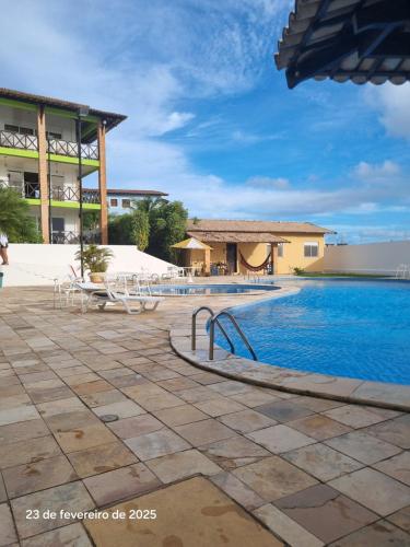 a resort with a swimming pool and a building at Condomínio Arituba Tropical - Praia Camurupim - Apartamento a 150m da praia in Nísia Floresta