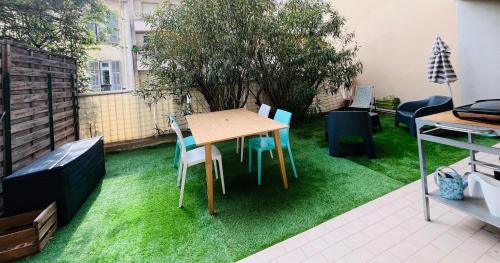 un patio avec une table et des chaises sur l'herbe dans l'établissement Appartement avec grande terrasse, à Nice