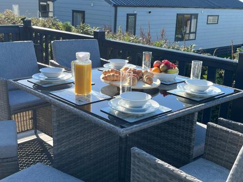 a table with food and drinks on a balcony at Stunning Lodge with sea and country views, sleeps 6 in Newquay