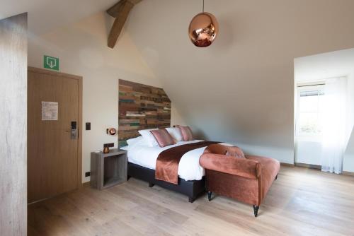 a bedroom with a king sized bed and a chair at Koru Hôtel & Private Wellness in Autre-Église