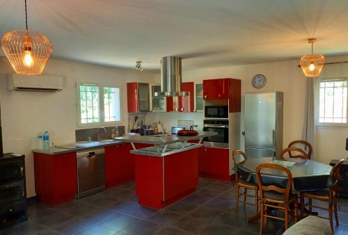 une cuisine avec des armoires rouges et une table et des chaises dans l'établissement villa des coteaux, à Ners
