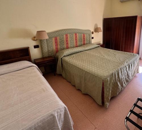 a hotel room with two beds and a lamp at Hotel Ely in Viareggio