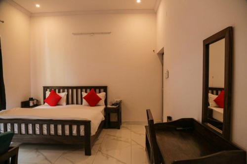 a bedroom with a bed with red pillows and a mirror at Brahma Heritage-Pool with Nature in Pushkar