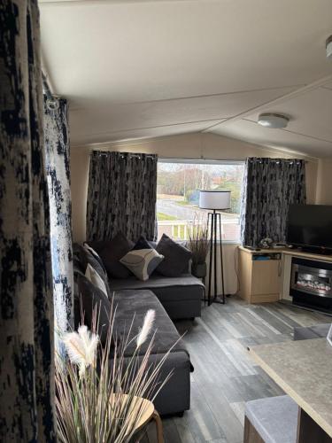 ein Wohnzimmer mit Sofa und Fernseher in der Unterkunft Rachel Retreat Caravan Kingfisher Court Tattershall Lake in Tattershall