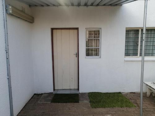 a white building with a door and a window at TRAVELASPA Guest House in Roodepoort