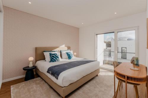 Un dormitorio con una cama y una mesa y una ventana. en Silver Coast Sunset View, en Atouguia da Baleia