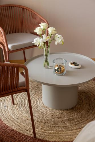 a white table with a vase of flowers on it at Metamare in Cozze