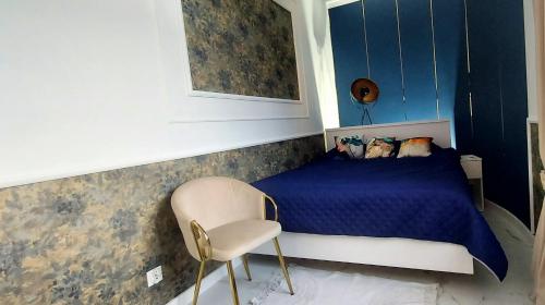 a bedroom with a blue bed and a chair at Apartament Azzurro - Old Town in Kłodzko