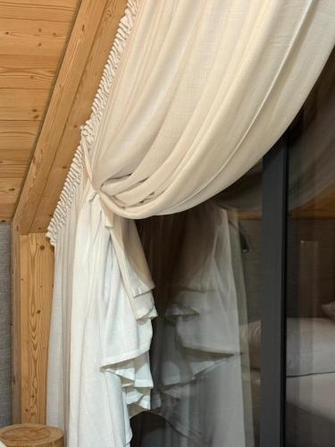 a window with white curtains in a bedroom at Yama Krywe in Krywe