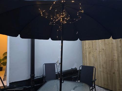 a table with a black umbrella and lights on it at 18 Anfield 5 min walk Sleeps 7 4BR 5Bed 3Bathrms in Liverpool