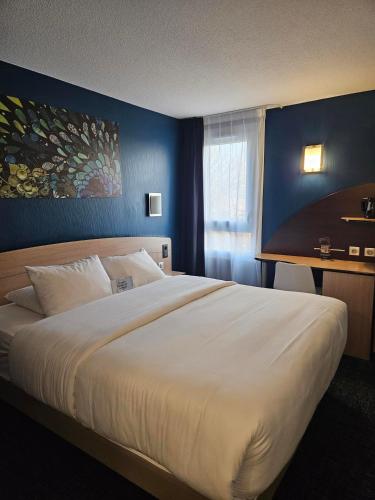 ein Schlafzimmer mit einem großen weißen Bett in einem Zimmer in der Unterkunft Kyriad Niort-Espace MendesFrance in Niort