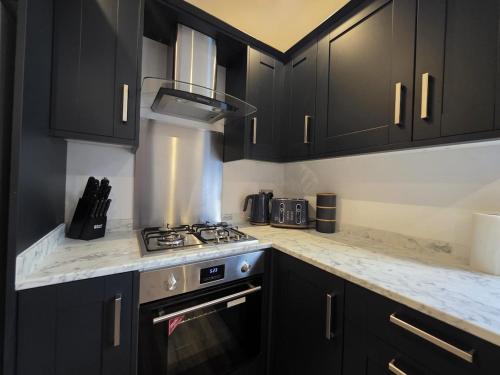 a kitchen with black cabinets and a stove top oven at 18 Anfield 5 min walk Sleeps 7 4BR 5Bed 3Bathrms in Liverpool