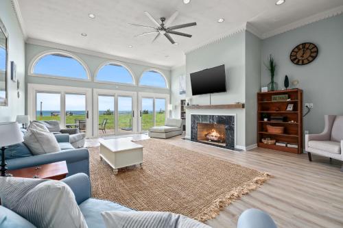 a living room with a fireplace and a tv at Sunset on the Rocks - Luxurious beachfront comfort! in Cape Charles