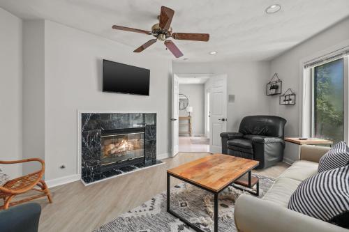 a living room with a fireplace and a ceiling fan at Sunset on the Rocks - Luxurious beachfront comfort! in Cape Charles