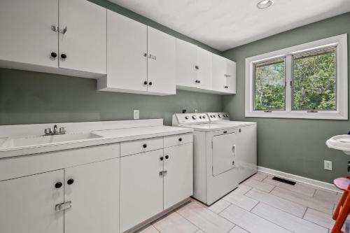 a white kitchen with white cabinets and a window at Sunset on the Rocks - Luxurious beachfront comfort! in Cape Charles