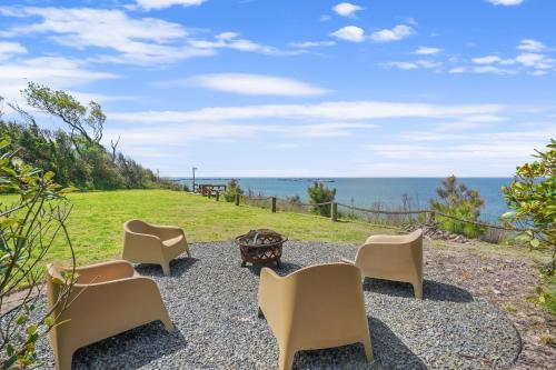 a group of chairs and a table and the ocean at Sunset on the Rocks - Luxurious beachfront comfort! in Cape Charles
