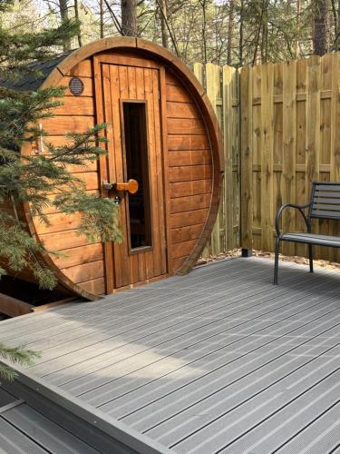 a wooden circle door on a deck with a bench at Konwaliowe Zacisze - chillout w leśnej aurze in Wilga