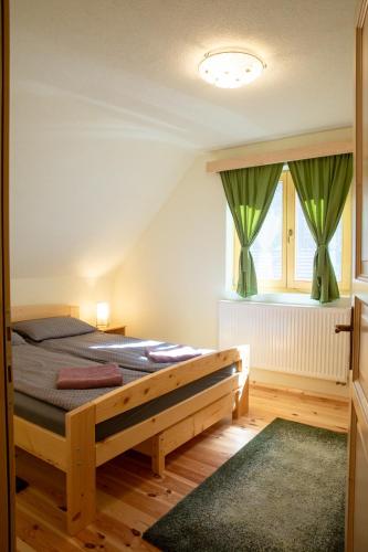 a bedroom with a bed and a window with green curtains at Két Patak Retreat in Bucsin