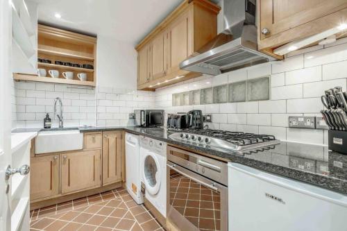 a kitchen with a stove and a washer and dryer at 2BR, garden, 60" TV with sound system in London