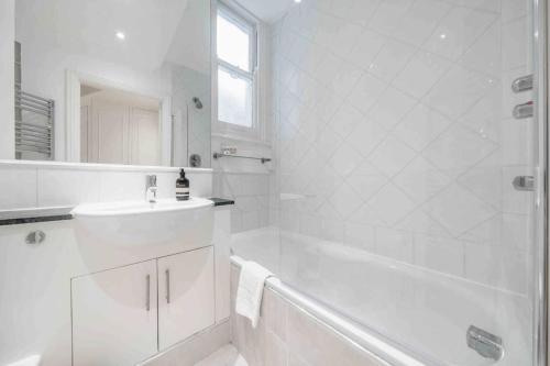 a white bathroom with a tub and a sink at 2BR, garden, 60" TV with sound system in London