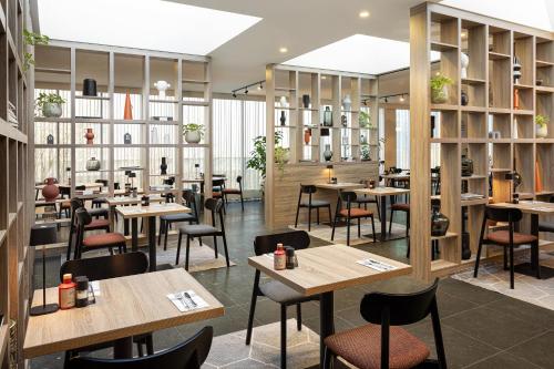 バドフーフェドルプにあるRamada by Wyndham Amsterdam Airport Schipholの木製のテーブルと椅子が備わるレストラン
