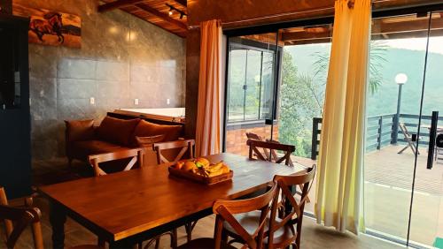 a dining room with a wooden table and a large window at Cabana Montana Viva Cada Momento in Guaramirim
