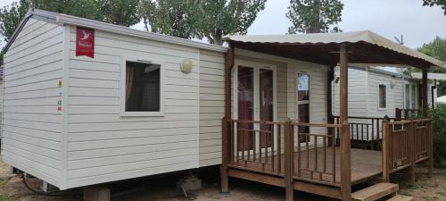 Cette petite maison blanche dispose d'une terrasse couverte et d'un kiosque. dans l'établissement Mobile home A32, à Sérignan