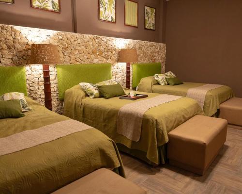 a room with three beds with green blankets at Hotel Nikché Mérida in Mérida
