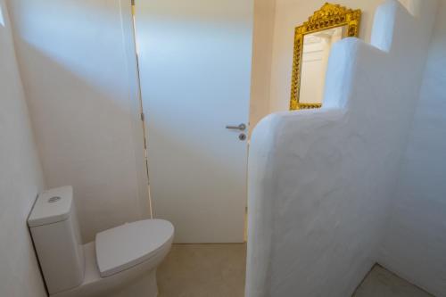a white bathroom with a toilet and a mirror at Valle D`Água - Casas de campo in Vale de Água