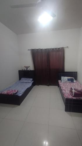 two beds in a room with a white floor at Furnished bad space for females in Sharjah